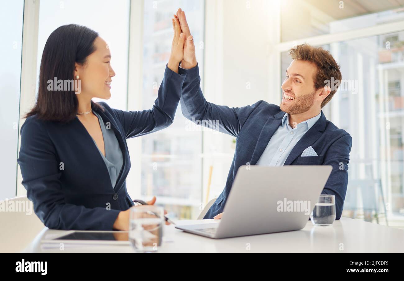 Two happy young diverse colleagues giving each other a high five while ...