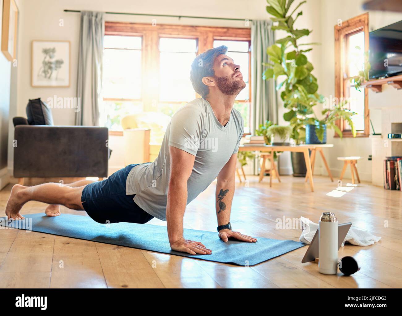 One fit young caucasian man doing cobra push up bodyweight exercise while training with online tutorial on digital tablet at home