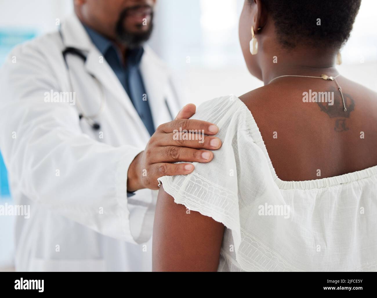 Doctor touching a patient on the shoulder in support. Closeup on hand of doctor being kind to a patient in a checkup. Medical gp offering a patient Stock Photo