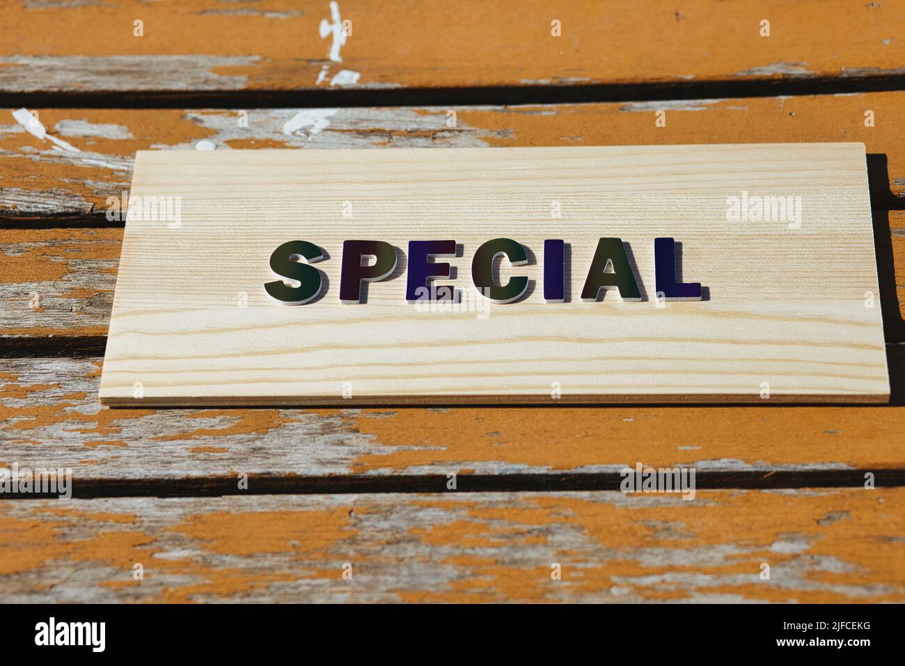 The word Special in rainbow colored lettering on an old rustic orange