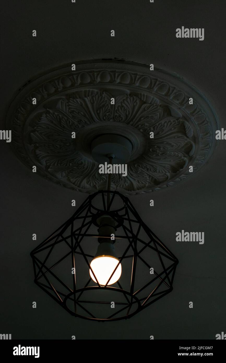 Light fitting fixture hanging metal hipster fitting around electric bulb with period ceiling