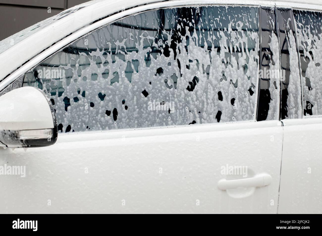Washing mirrors in a white car with active foam. Car wash Stock Photo Alamy