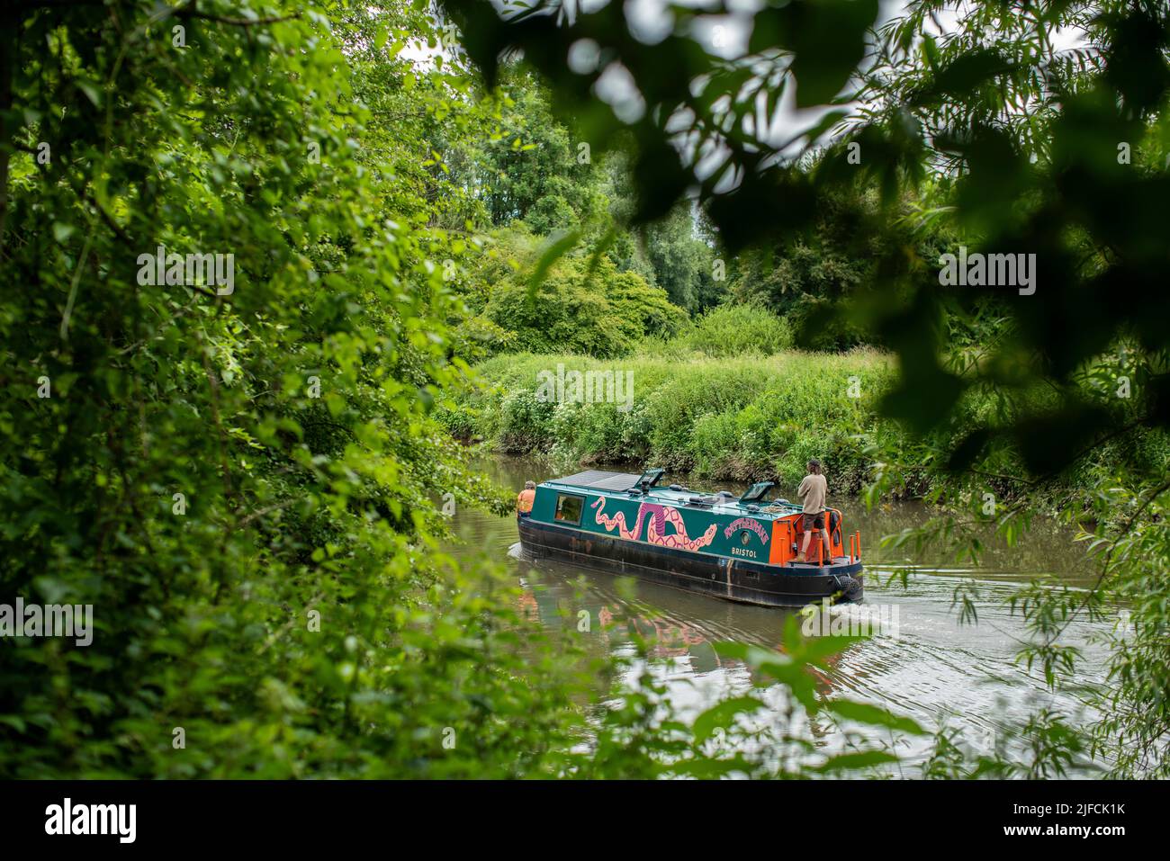 A house boat makes its way along the River Avon towards Bath through Conham River Park in east Bristol on a sunny summer day. Stock Photo