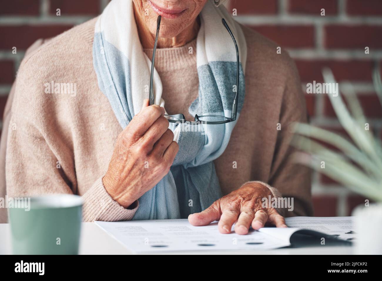 Mature woman reading financial insurance documents at home.A senior woman reading financial paperwork planning her retirement. A mature woman holding Stock Photo