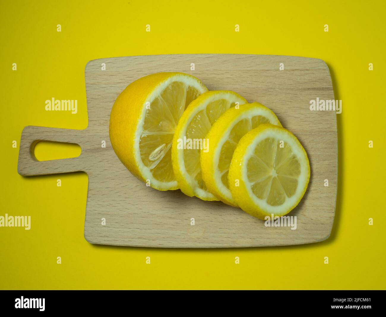 https://c8.alamy.com/comp/2JFCM61/a-sliced-lemon-on-a-small-cutting-board-on-a-yellow-background-citrus-on-the-table-bright-background-healthy-fortified-food-for-a-diet-sour-produ-2JFCM61.jpg