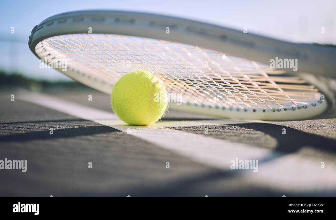 Below shot of a tennis racquet and tennis ball on a sports court. The only tools a professional tennis player needs to participate in their chosen Stock Photo