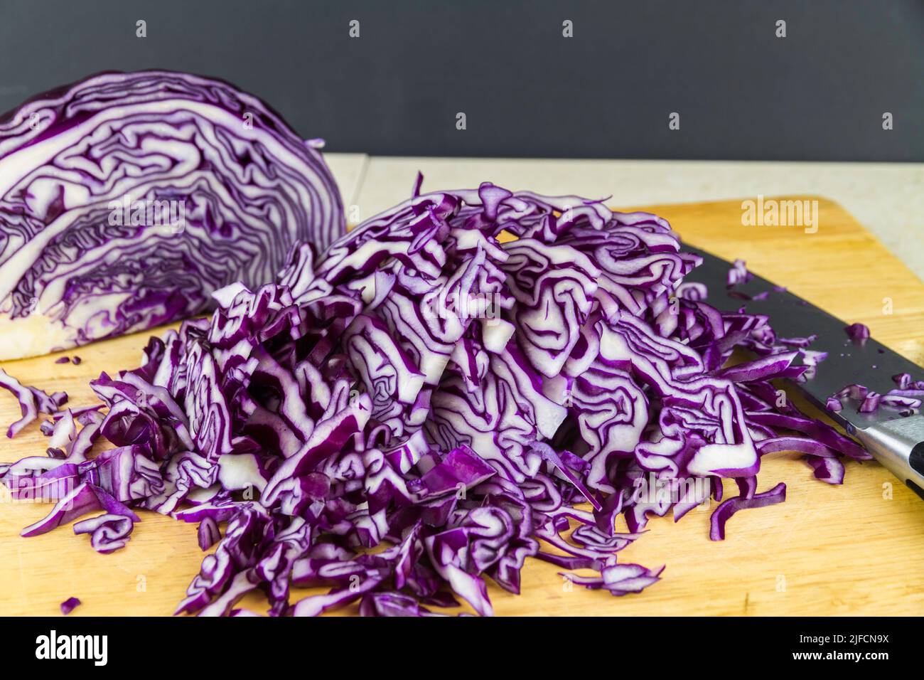 Shredded red cabbage on a  chopping board with knife, landscape. Stock Photo