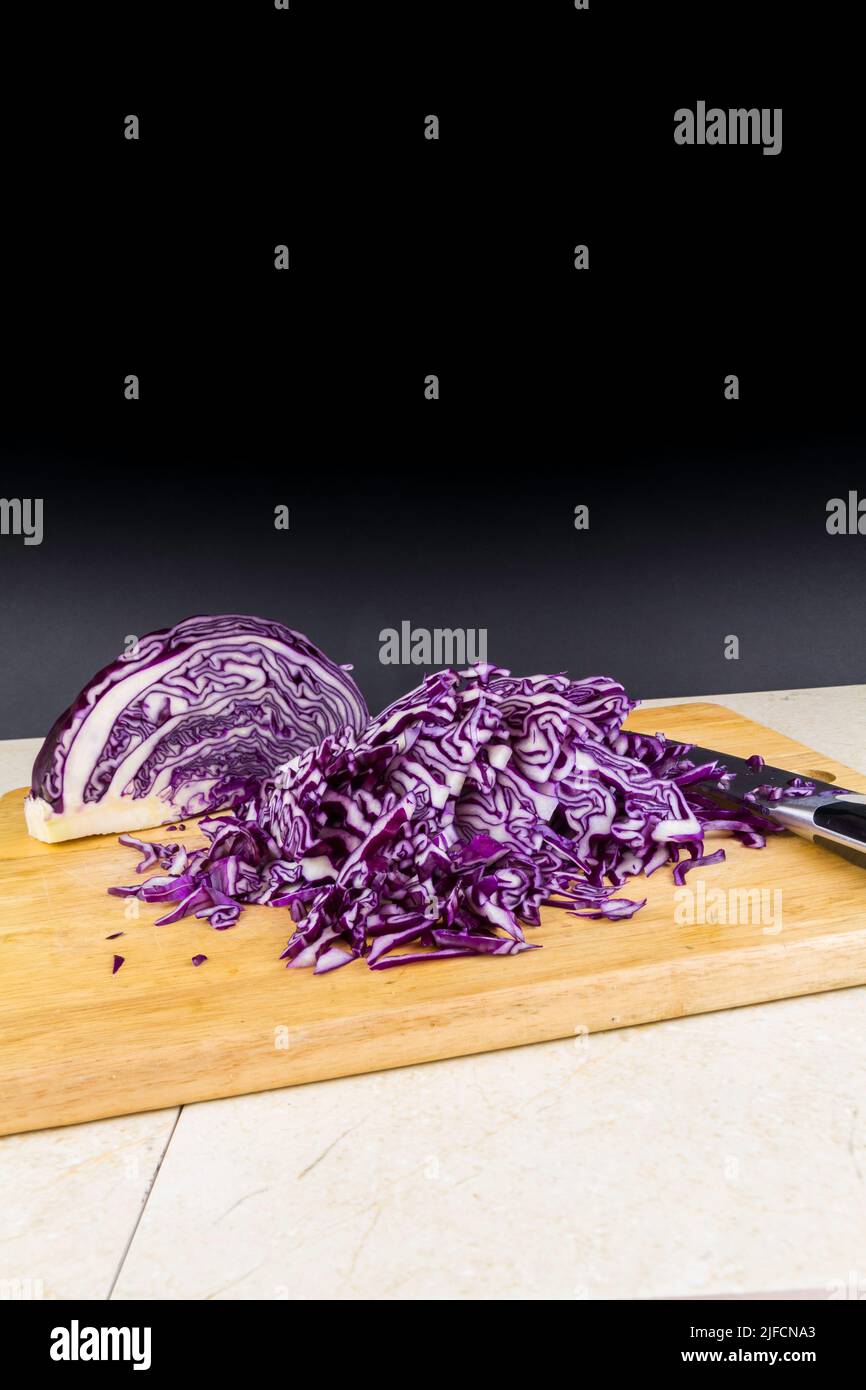 Shredded red cabbage on a  chopping board portrait, black copyspace at top. Stock Photo