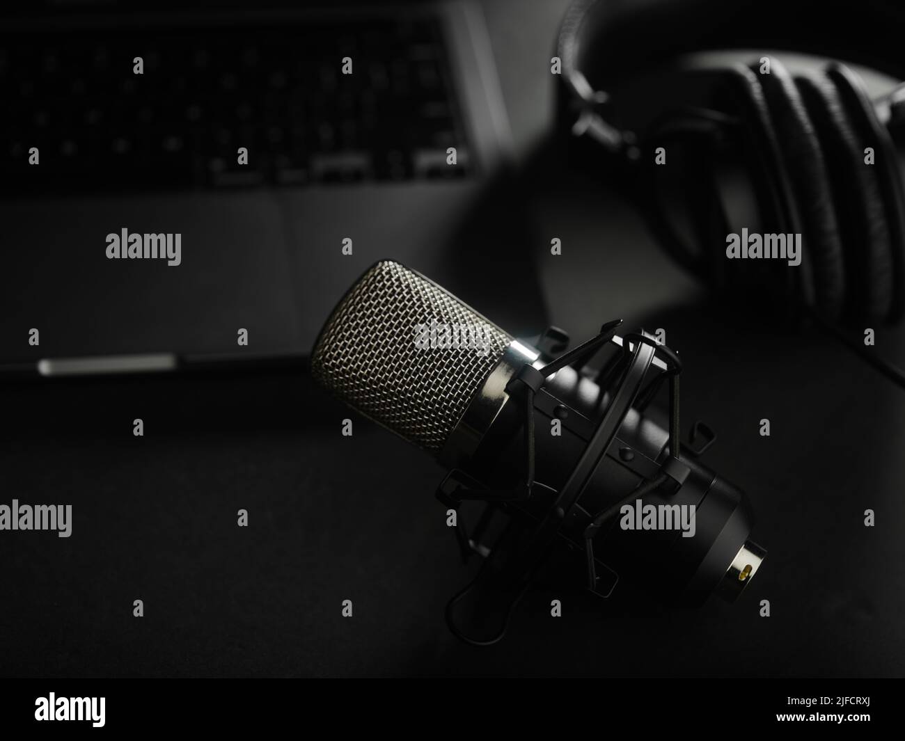On a dark gray background, a laptop, studio headphones and a studio