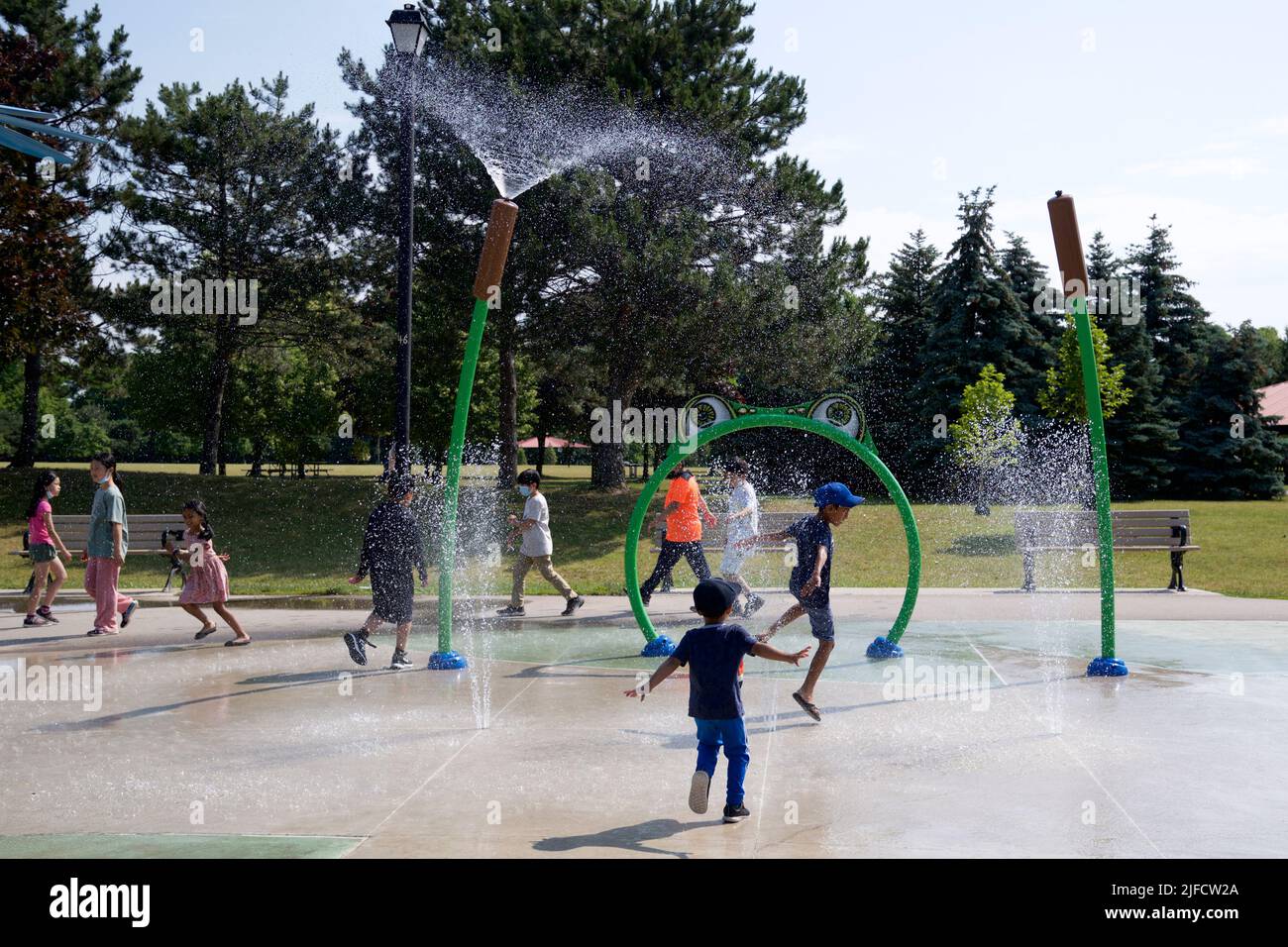 Toronto, Ontario / Canada - 06/30/2022: Children bathing in a refreshing spray of the city fountain on a hot summer day. Children playing in spray par Stock Photo