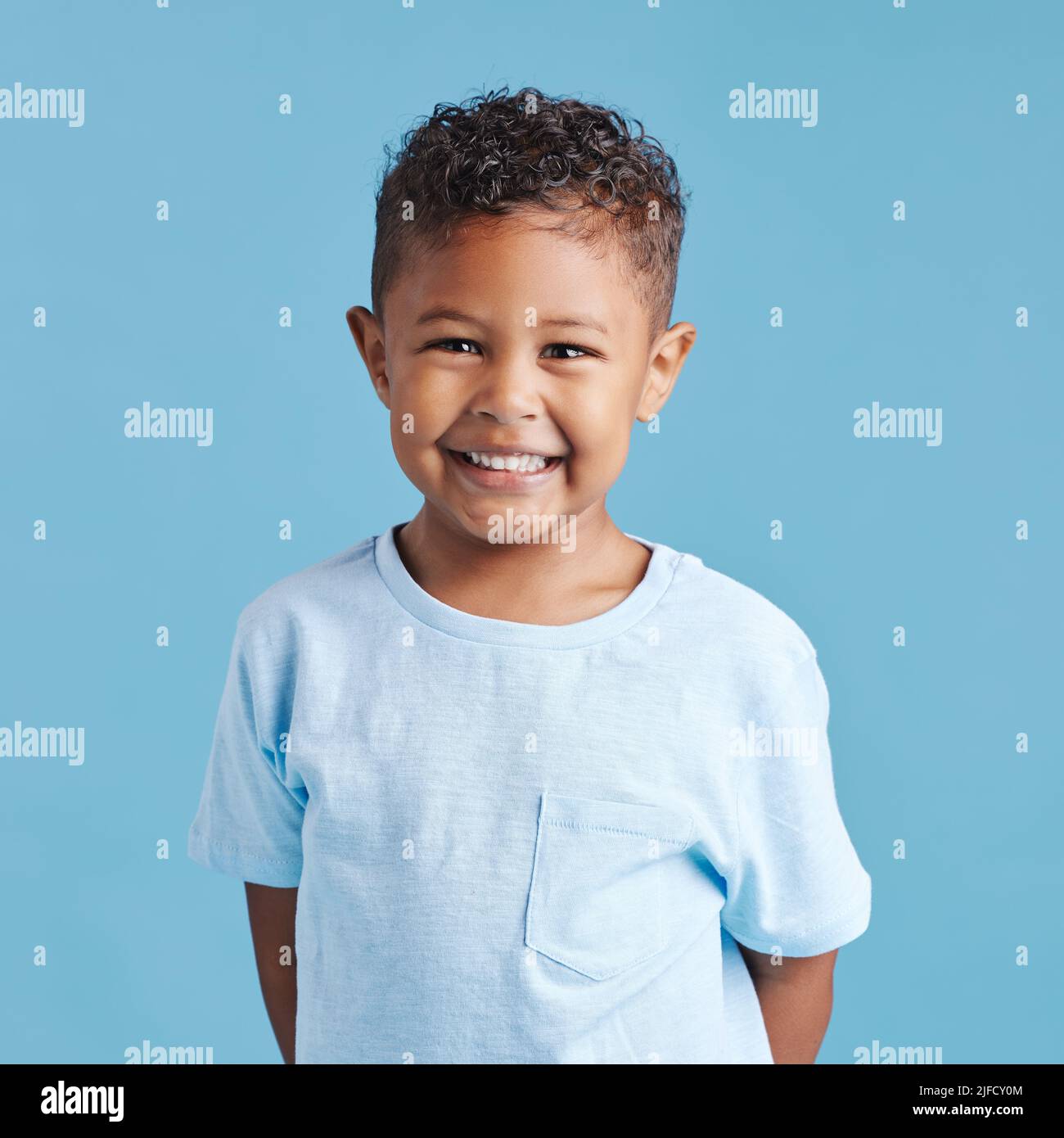 Portrait of a smiling little brown haired boy looking at the camera. Happy kid with good healthy teeth for dental on blue background Stock Photo