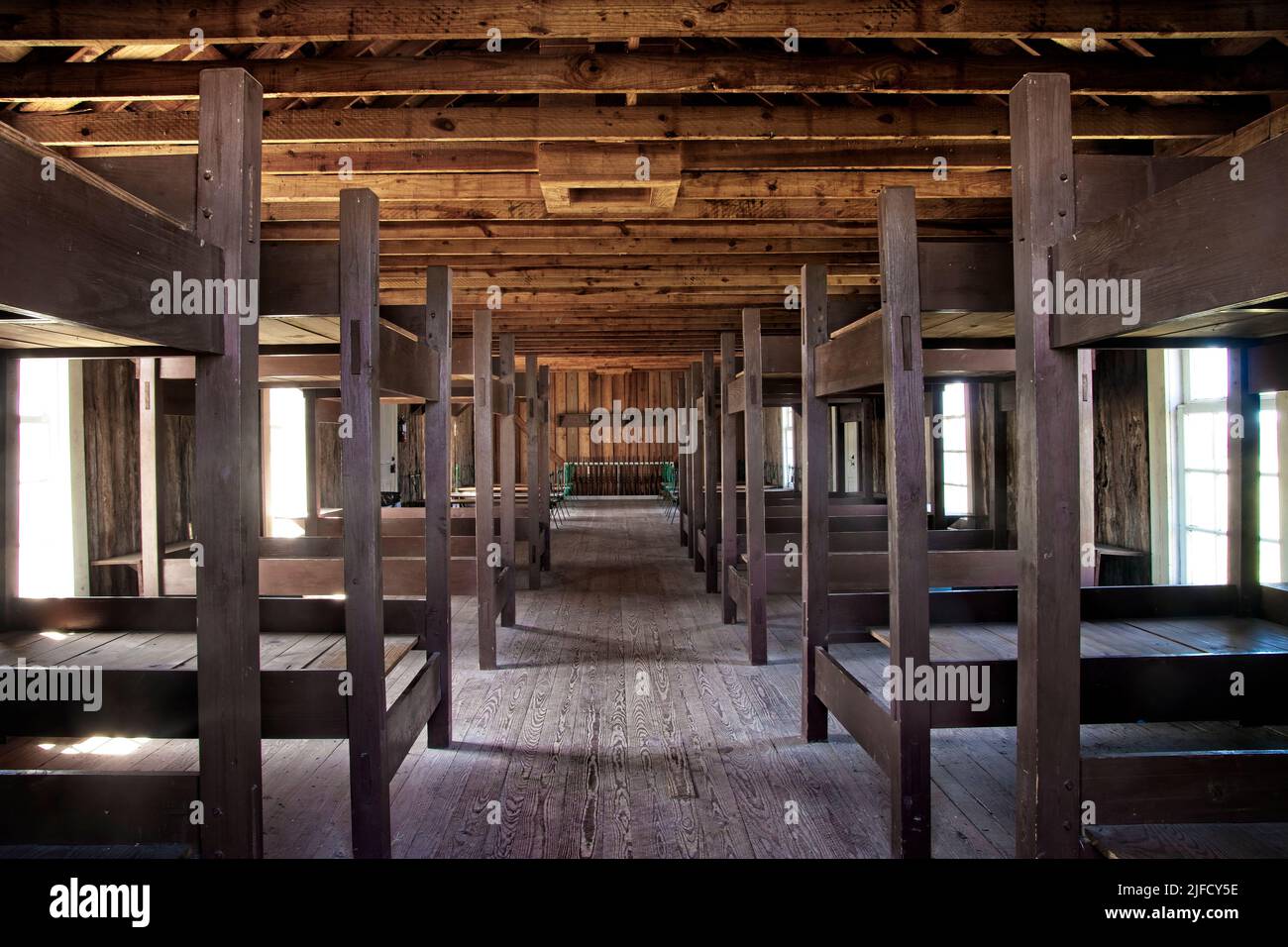 Natural lighting exposes interior of western military barracks with gun