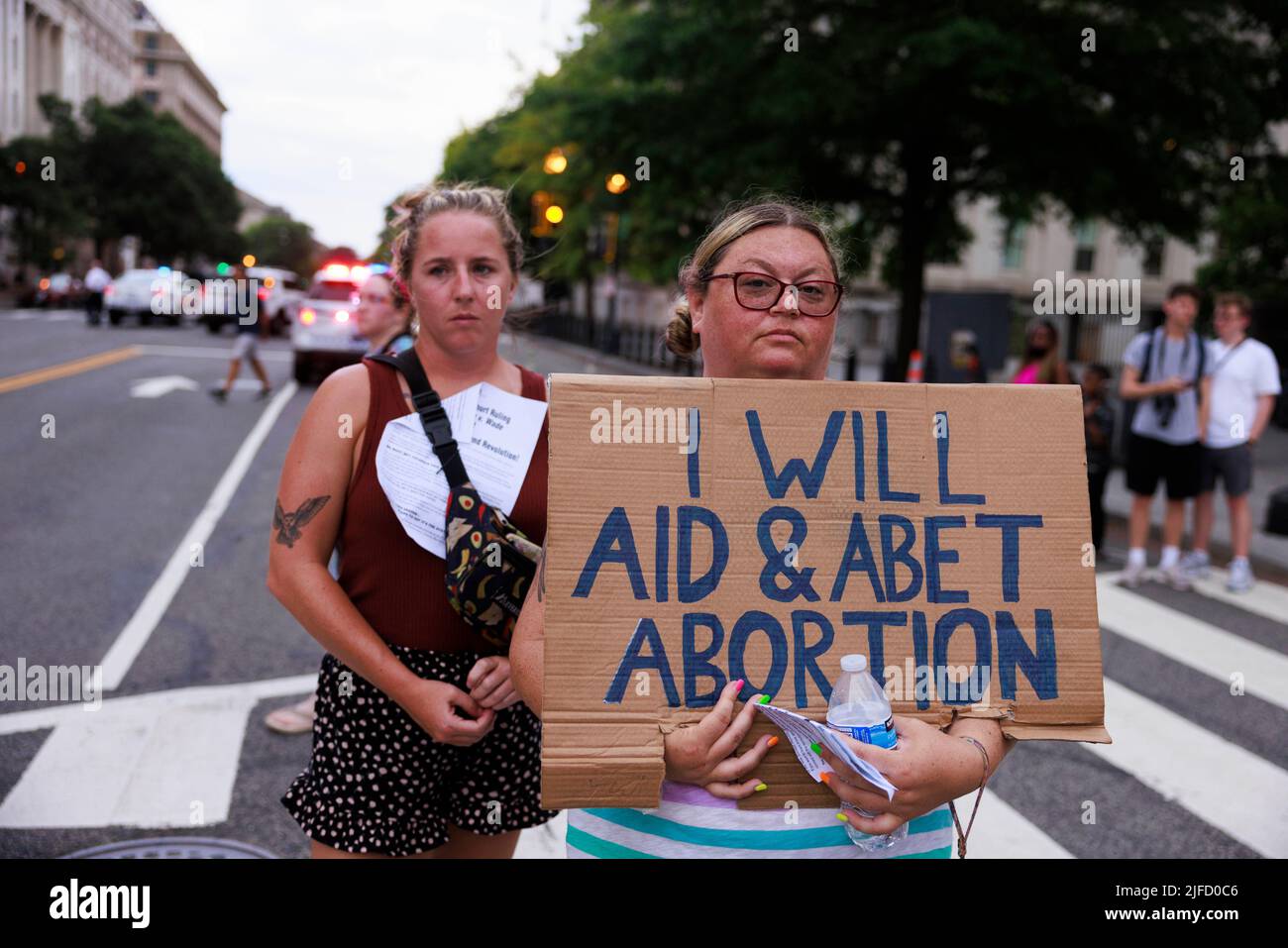WASHINGTON, DISTRICT OF COLUMBIA - JUNE 26: An abortion-rights activist holds a sign reading, “I will aid and abet abortion,” near the White House in protest two days after a conservative majority struck down Roe v Wade, on June 26, 2022 in Washington, District of Columbia. The Court's decision in Dobbs v Jackson Women's Health overturns the landmark 50-year-old Roe v Wade case and erases a federal right to an abortion. Stock Photo