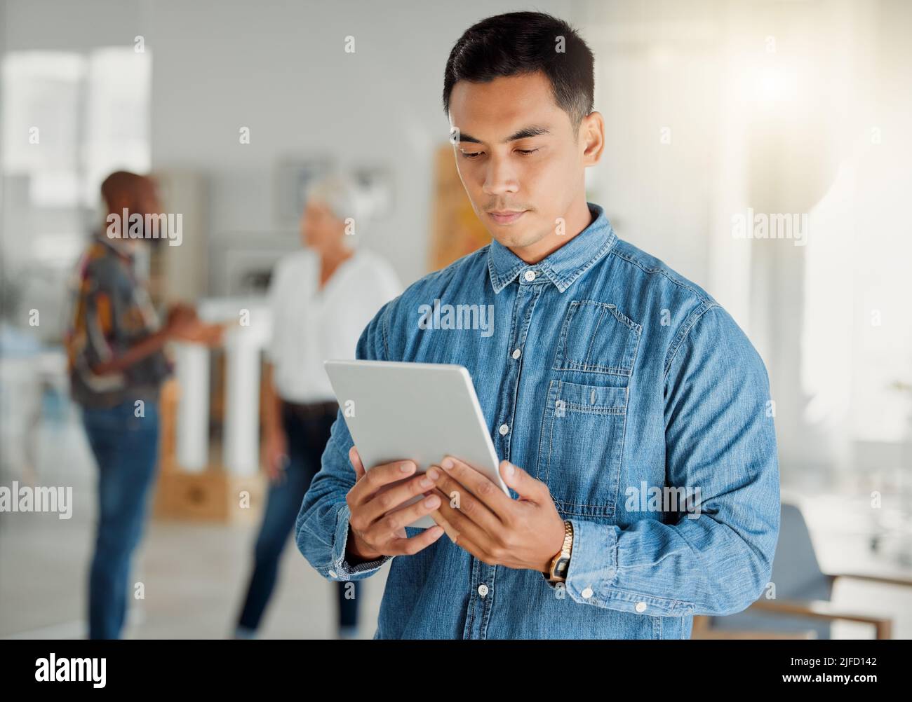 Serious asian businessman holding and using a digital tablet at work ...