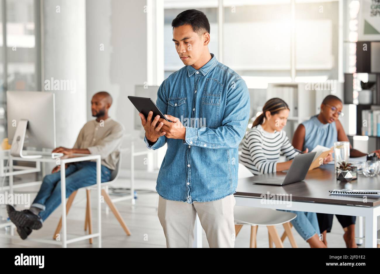 Focused mixed race businessman working on a digital tablet at work. Serious hispanic man using social media on a digital tablet. Businessperson Stock Photo