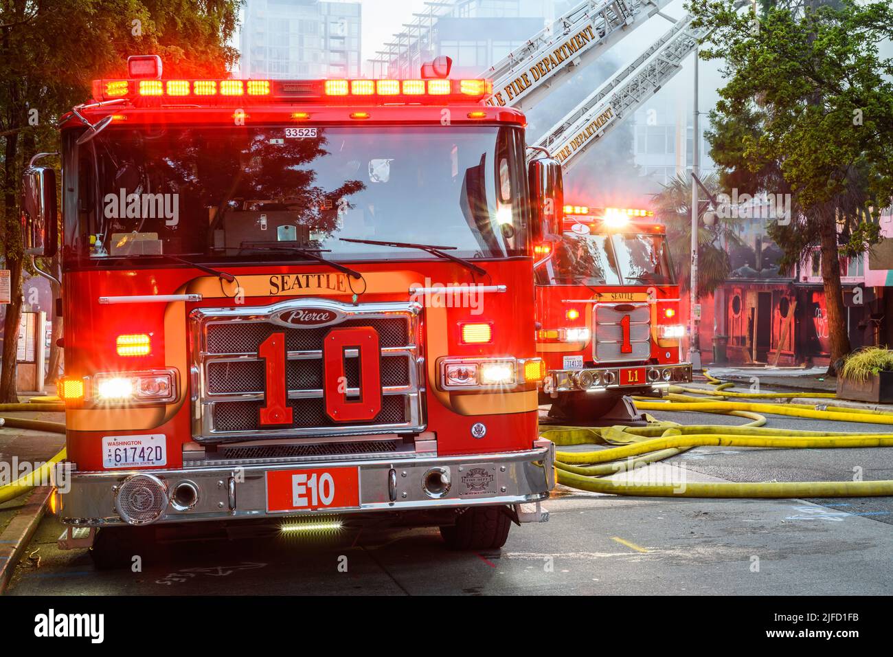 Seattle - June 30, 2022; City of Seattle fire department ladder trucks with yellow hoses.  This is a two alarm fire in the Belltown neighborhood Stock Photo