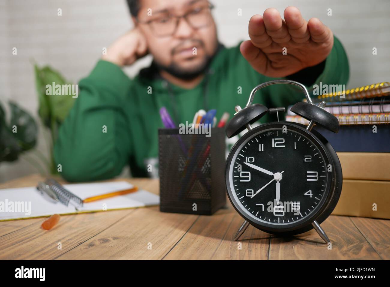 frustrated bot stopping his alarm clock while studying  Stock Photo