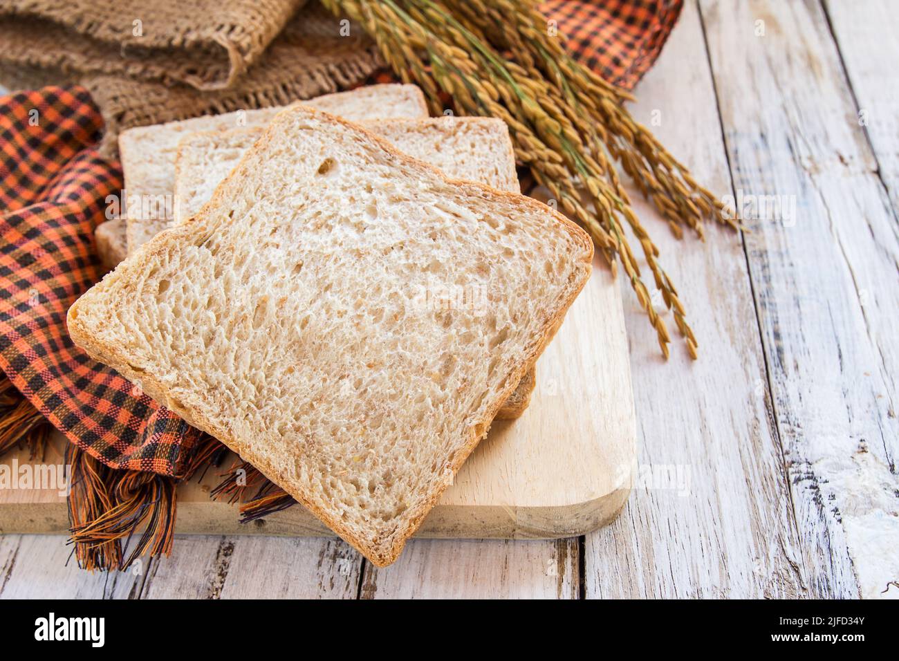 Whole wheat bread and spike on white wooden table background Stock ...
