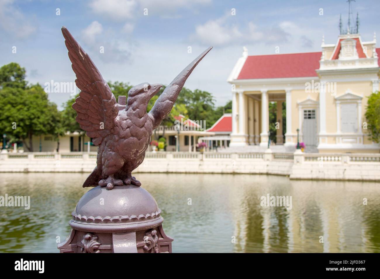 The closeup image of eagle statue. The bokeh background is The Phra Thinang Warophat Phiman in Bang Pa-In Palace Ayutthaya Thailand. Stock Photo