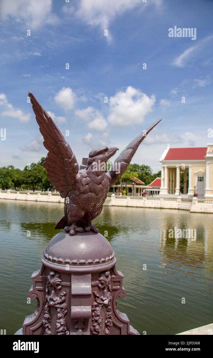 The closeup image of eagle statue. The bokeh background is The Phra Thinang Warophat Phiman in Bang Pa-In Palace Ayutthaya Thailand. Stock Photo