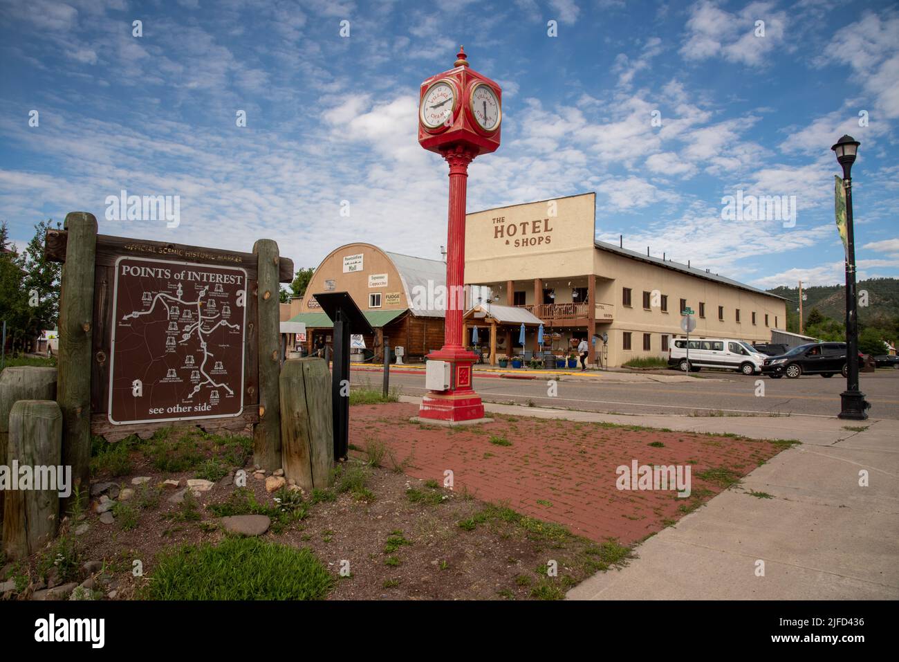 Downtown Chama, New Mexico, looking across a sign marking points of interest, a bright red pedestal clock and The Hotel and Shops. Stock Photo