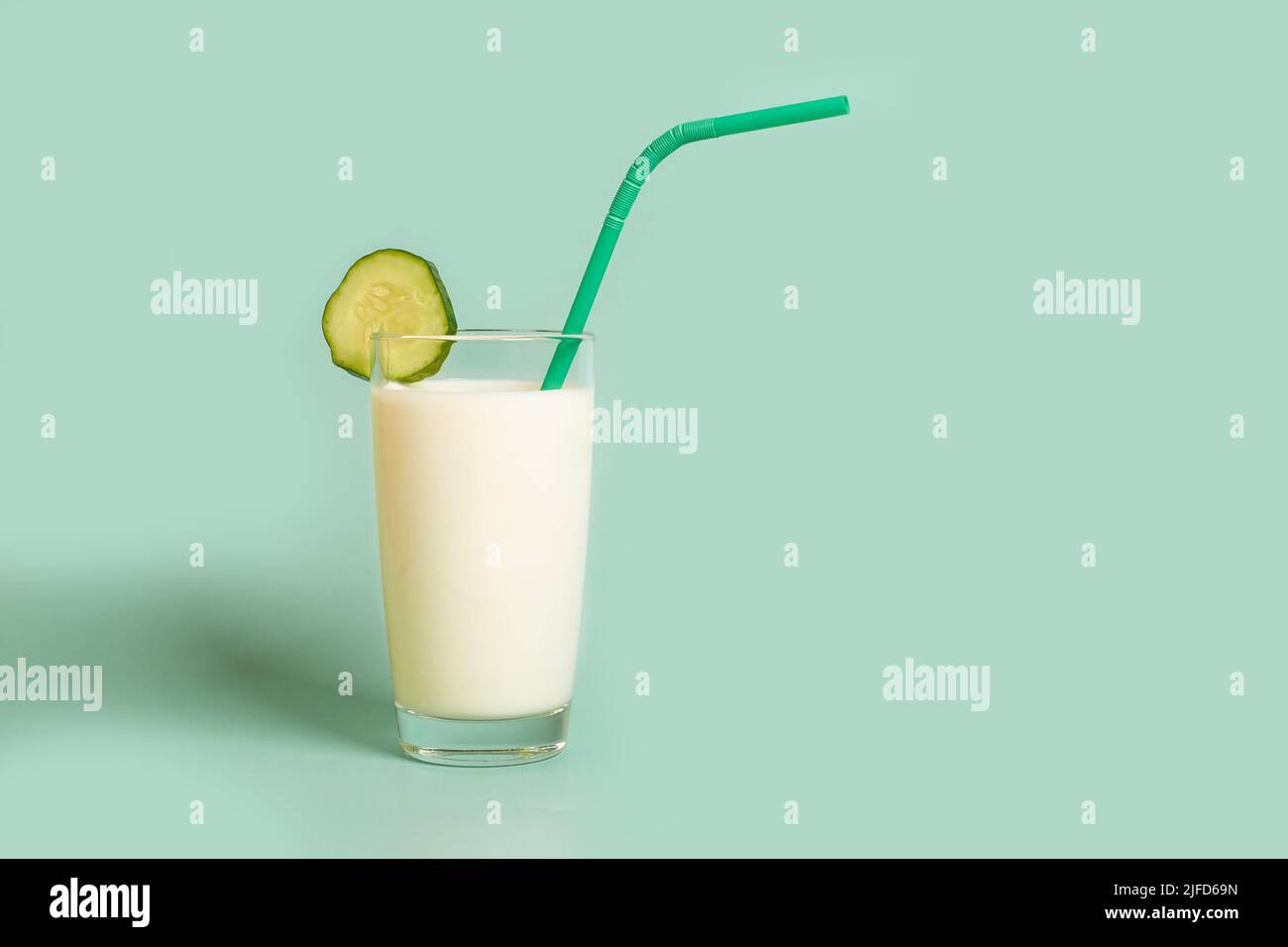 Glass with milk, plastic tube and cucumber slice Stock Photo