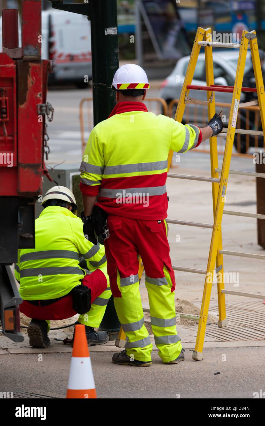 Two electrician worker fixing a traffic light in city street Stock