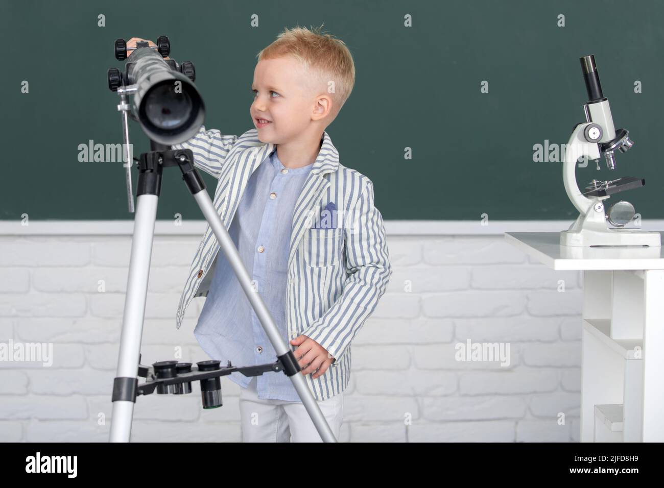 School kid with telescope learning astronomy lesson at school Stock