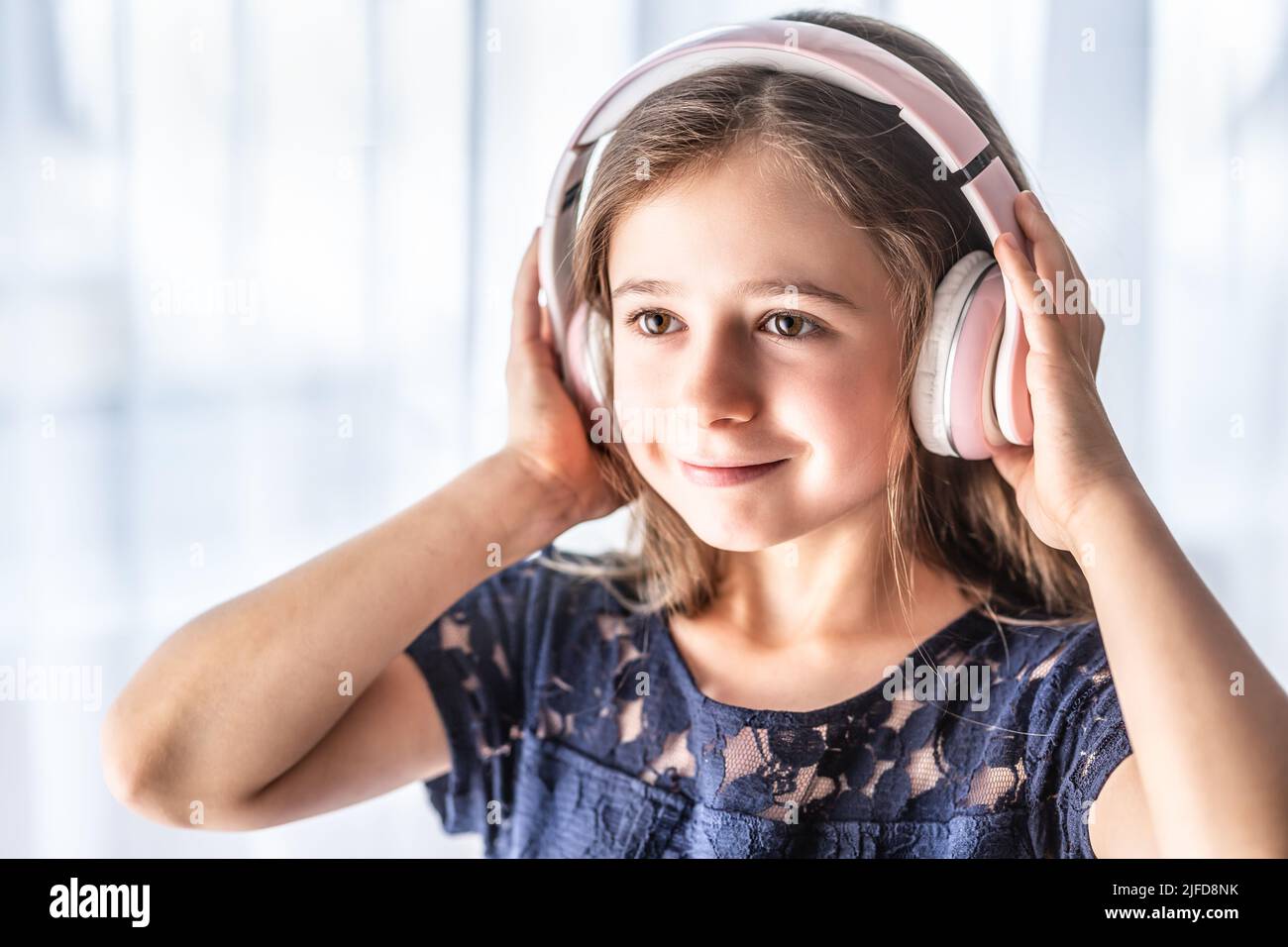 A small child listens to music through wireless headphones. Stock Photo