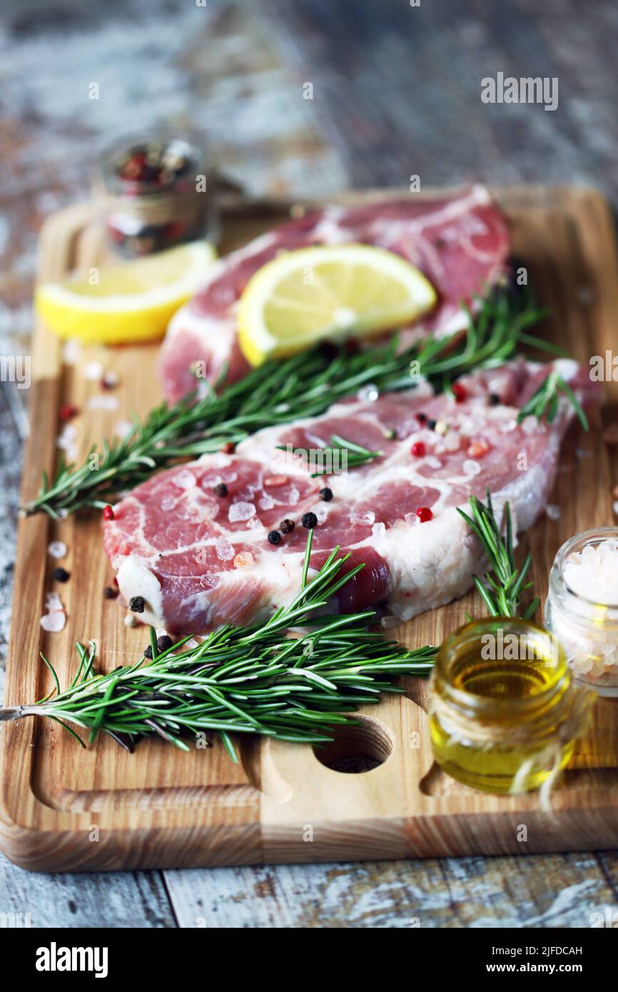 Raw pork steaks with rosemary, coarse salt and lemon. Fresh pork. Neck