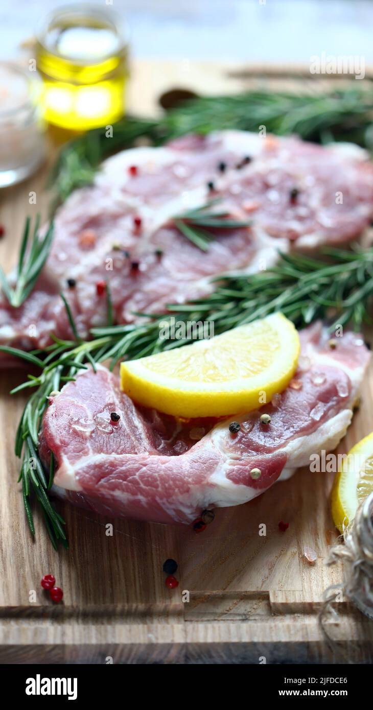 Raw pork steaks with rosemary, coarse salt and lemon. Fresh pork. Neck