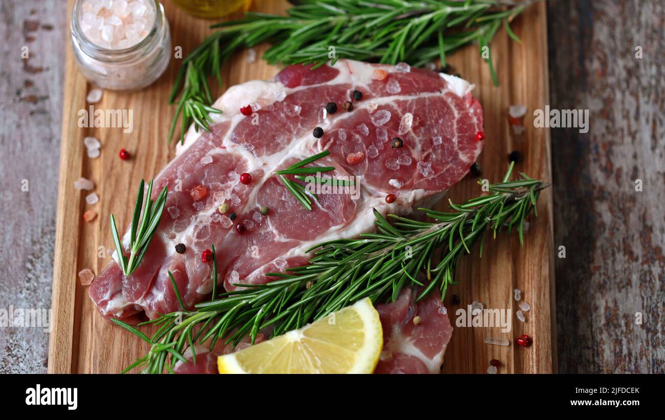 Raw pork steaks with rosemary, coarse salt and lemon. Fresh pork. Neck