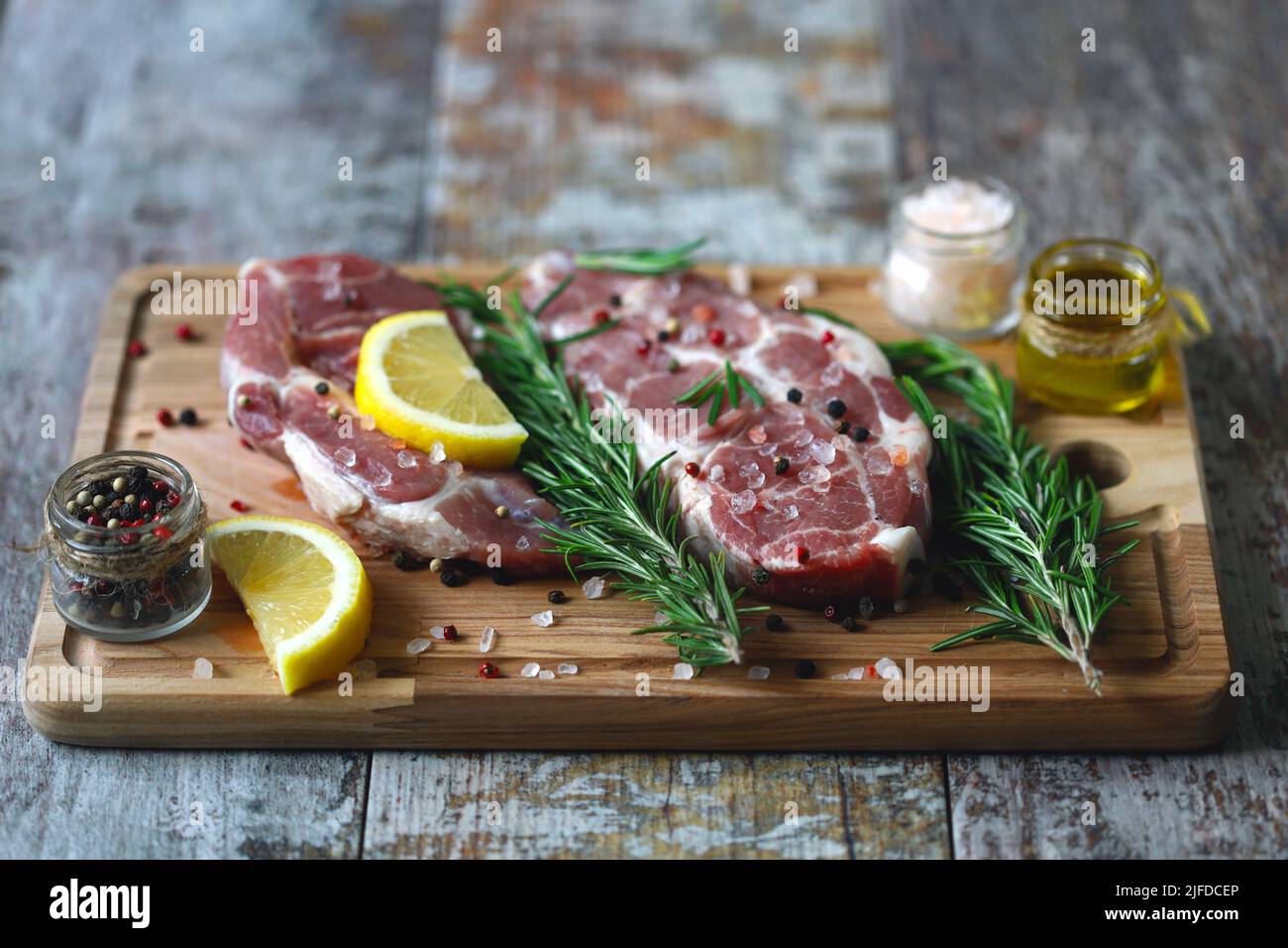 Raw pork steaks with rosemary, coarse salt and lemon. Fresh pork. Neck