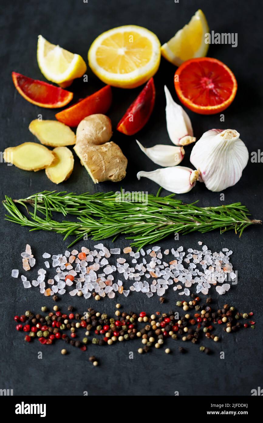 . Set spice on a black stone board. Peppers mix, Himalayan salt, rosemary, garlic, lemon, ginger, red orange. Stock Photo