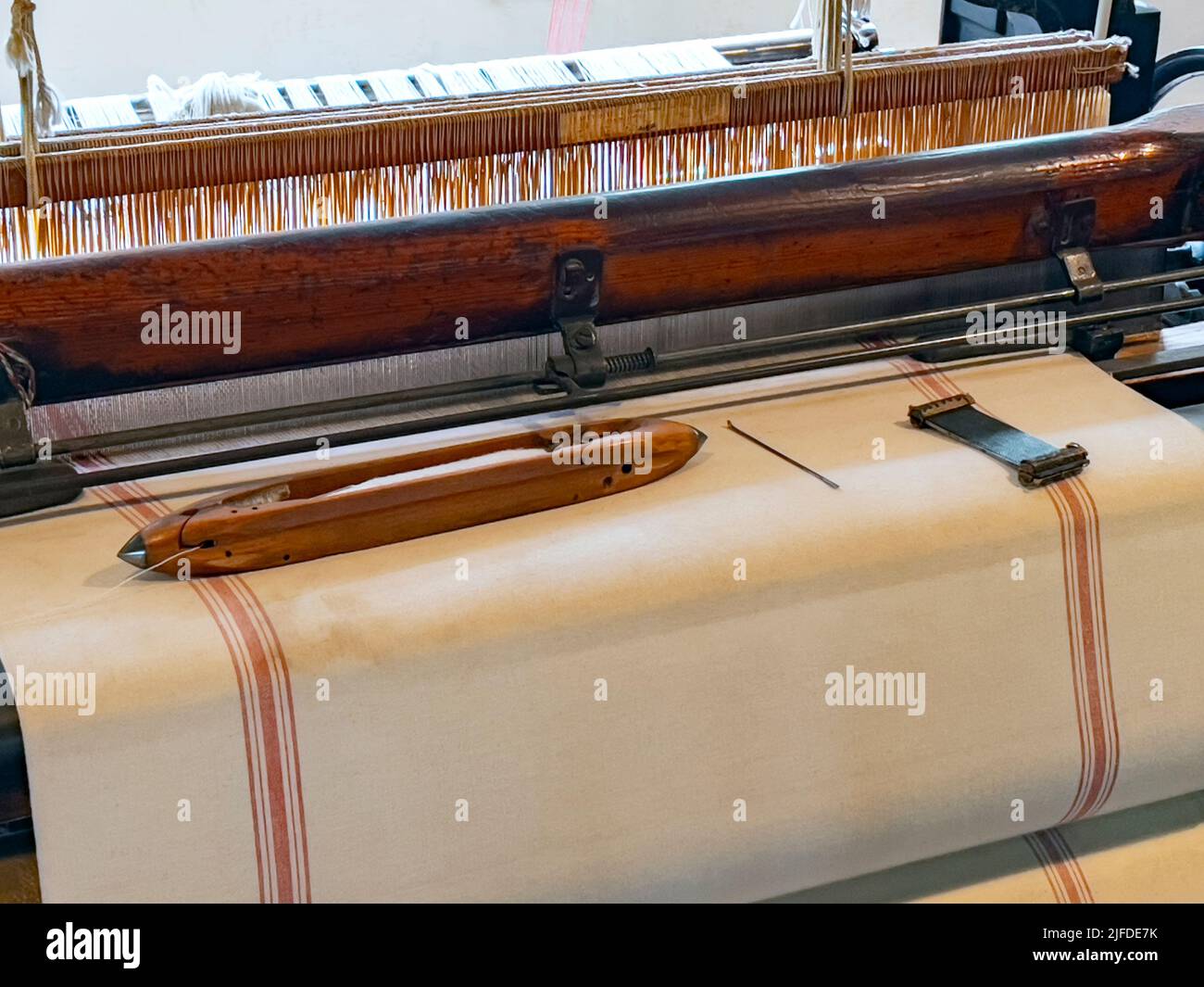 Weaving loom with cotton fabric and shuttle. A loom is a device used to