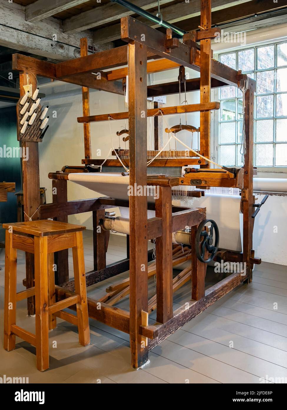 A simple hand-operated loom. A loom is a device used to weave cloth and tapestry. The basic purpose of any loom is to hold the warp threads under tens Stock Photo
