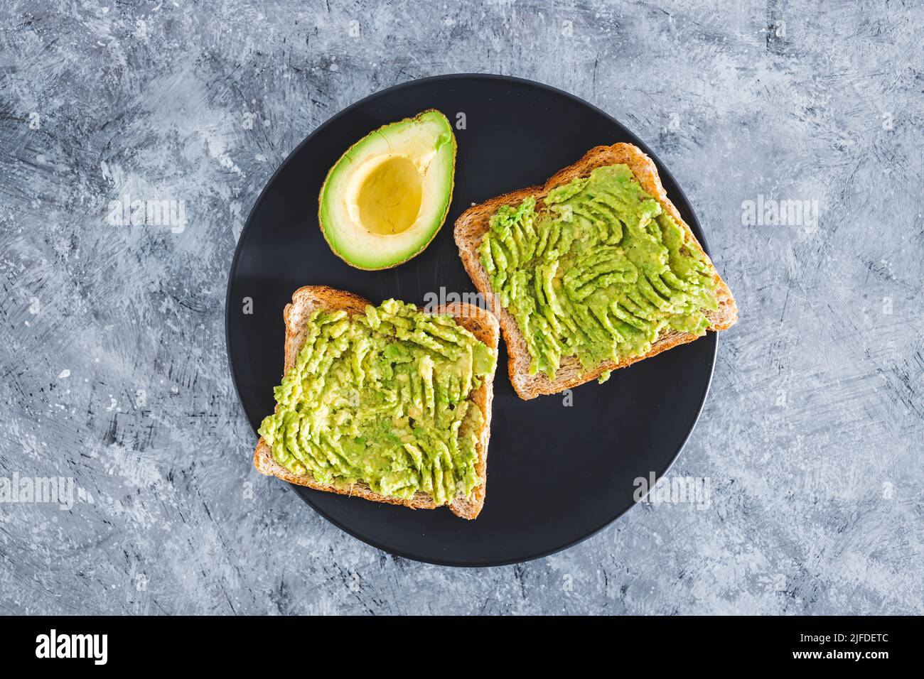 basic plantbased smashed avocado toast with half avocado next to it