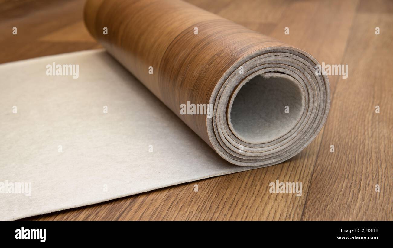 An expanded roll of brown linoleum. Closeup side view. Linoleum with wood structure lies on the