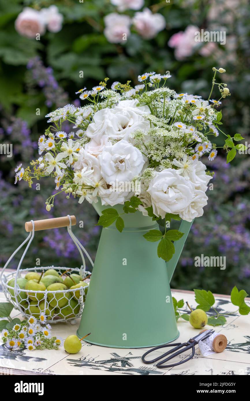 bouquet of white roses, wild asters and wild carrots in vintage jug in garden Stock Photo