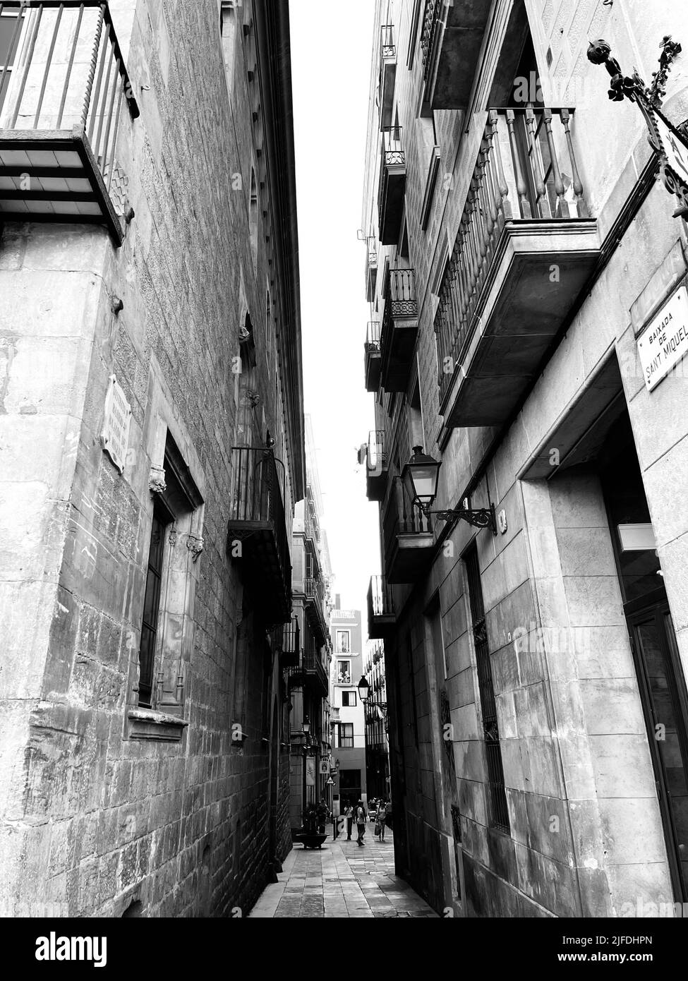 A vertical grayscale shot of a narrow street between two buildings ...