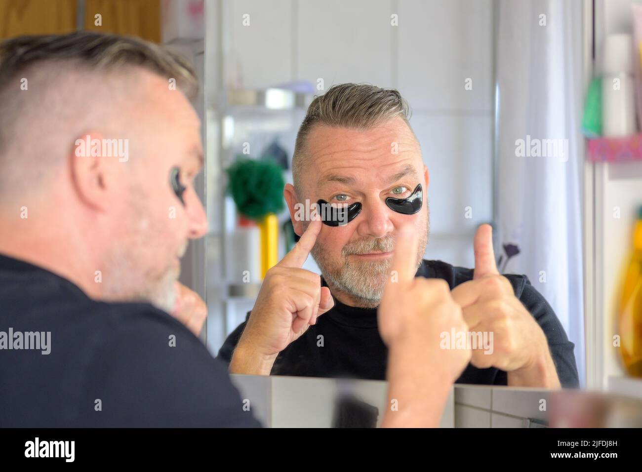 Senior man pointing to hydrating gel eye patches while giving a thumbs