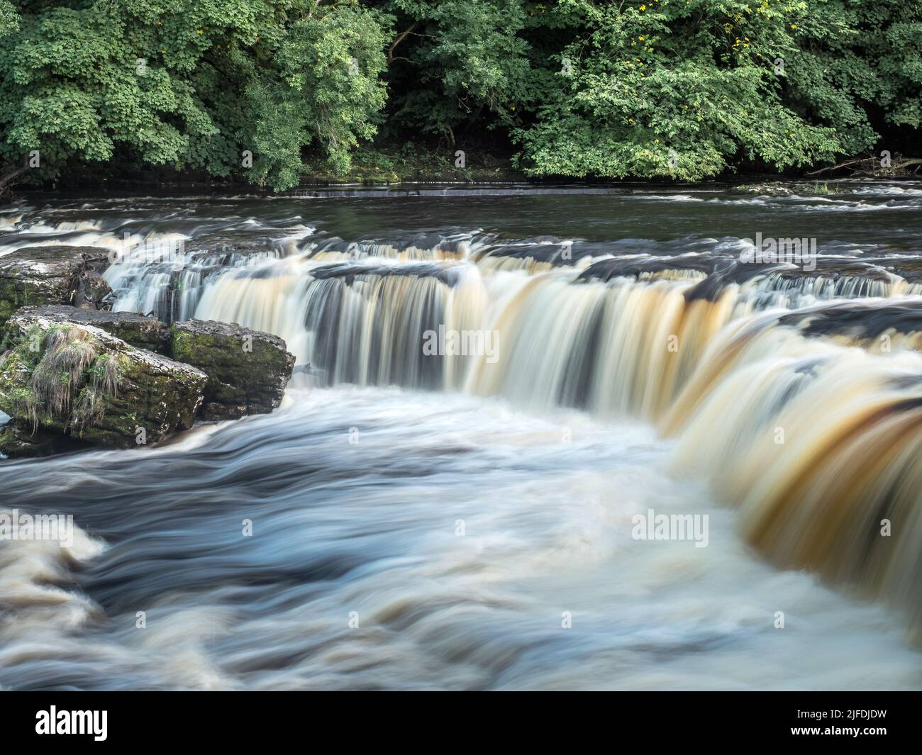 Aysgarth Falls are a triple flight of waterfalls, surrounded by forest carved out by the River Ure on its descent through Wensleydale in the Yorkshire Stock Photo