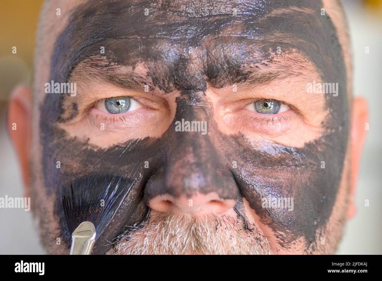 Extreme close up cropped view the face of a man wearing a cosmetic face