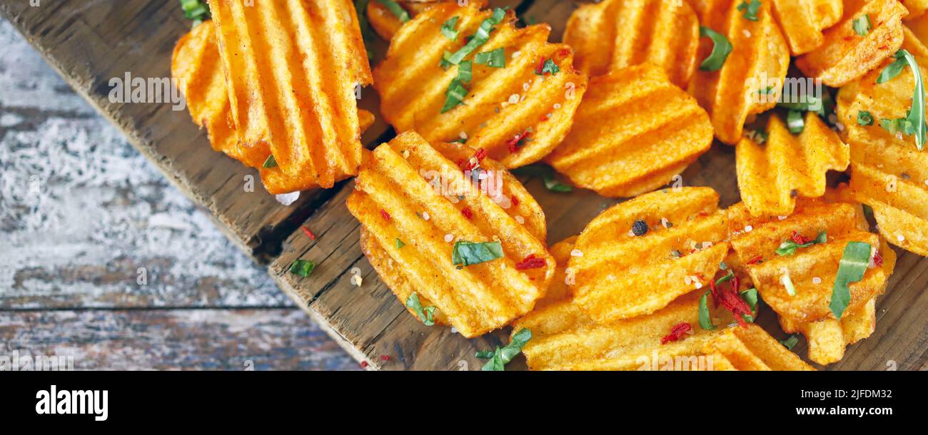 Chips with spices on a wooden surface. Unhealthy food. Highcalorie