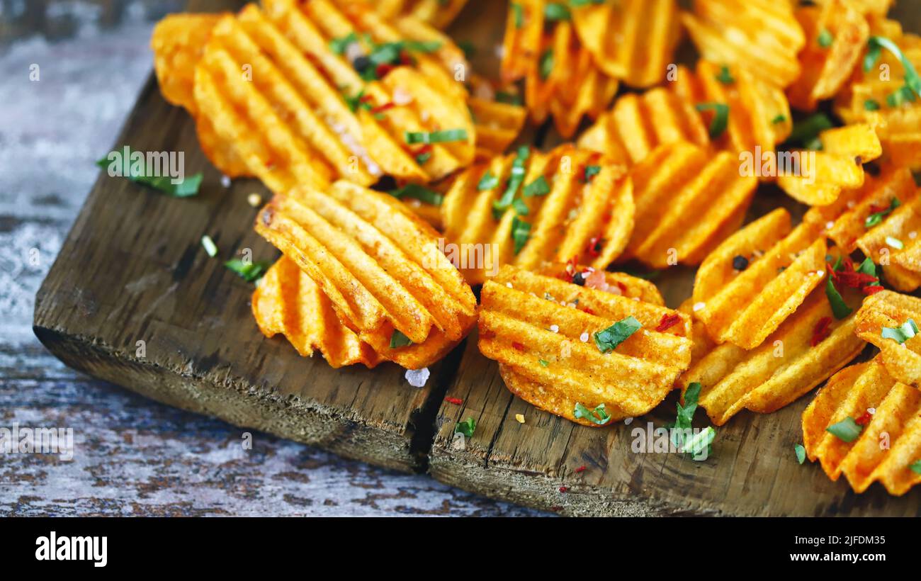 Chips with spices on a wooden surface. Unhealthy food. Highcalorie