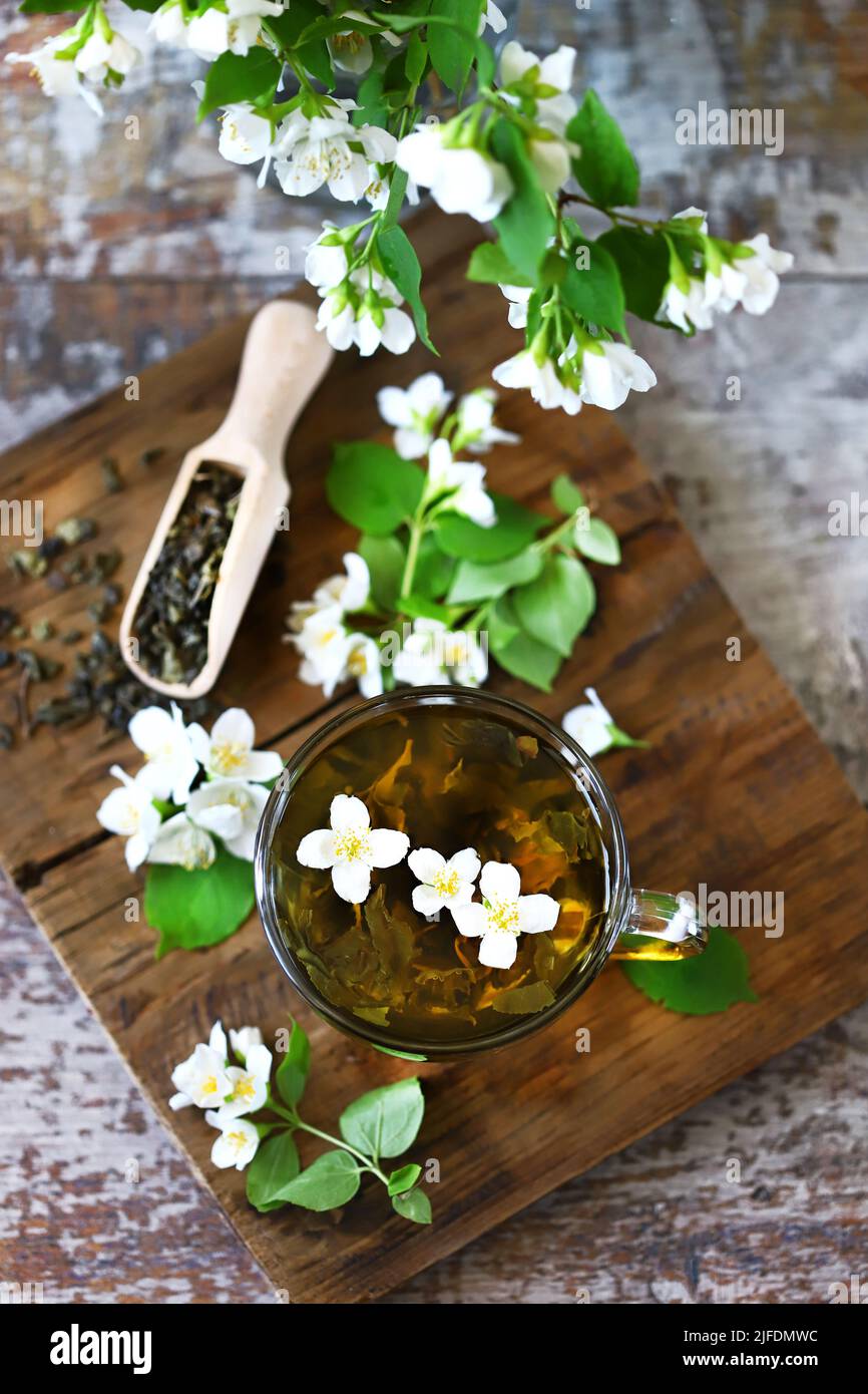 jasmine green tea in a cup. Jasmine flowers, dry tea on a wooden surface. Stock Photo