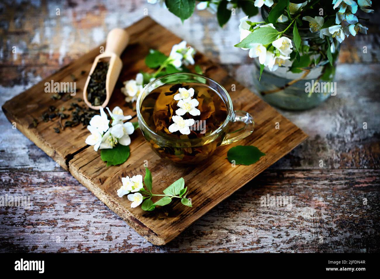 jasmine green tea in a cup. Jasmine flowers, dry tea on a wooden surface. Stock Photo