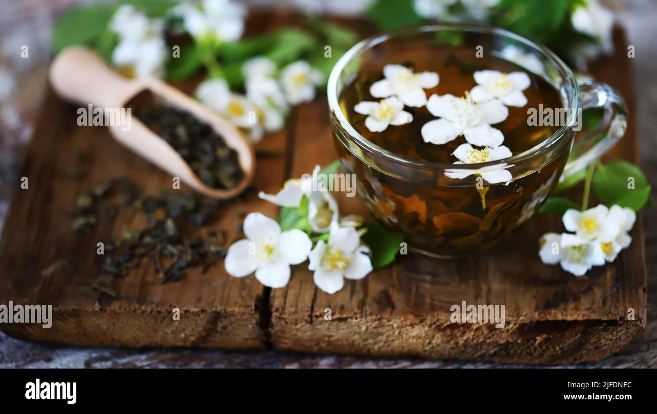 jasmine green tea in a cup. Jasmine flowers, dry tea on a wooden surface. Stock Photo