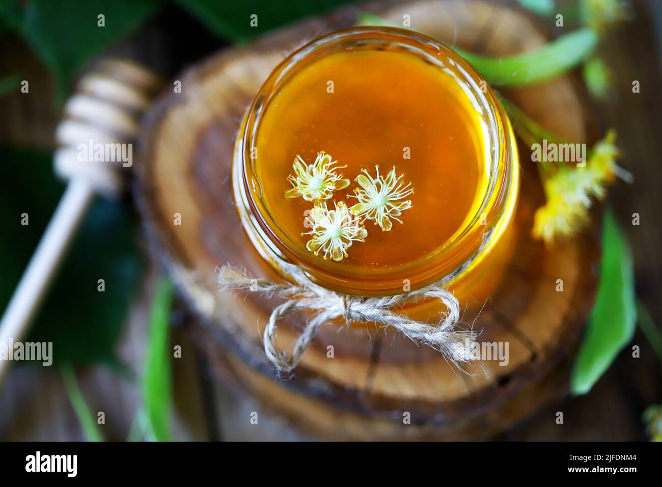 Linden honey in a jar. Leaves and flowers of linden. Freshly linden honey. Stock Photo