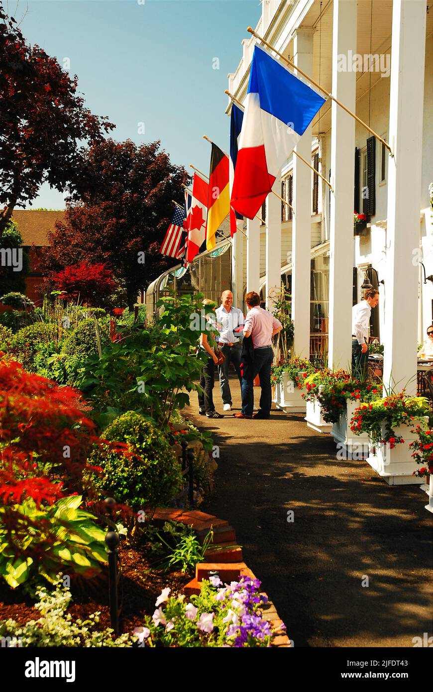 People talk under the flags of several nations in front of the Beakman Arms Inn, said to be the oldest inn in America, near Rhinebeck, New York Stock Photo